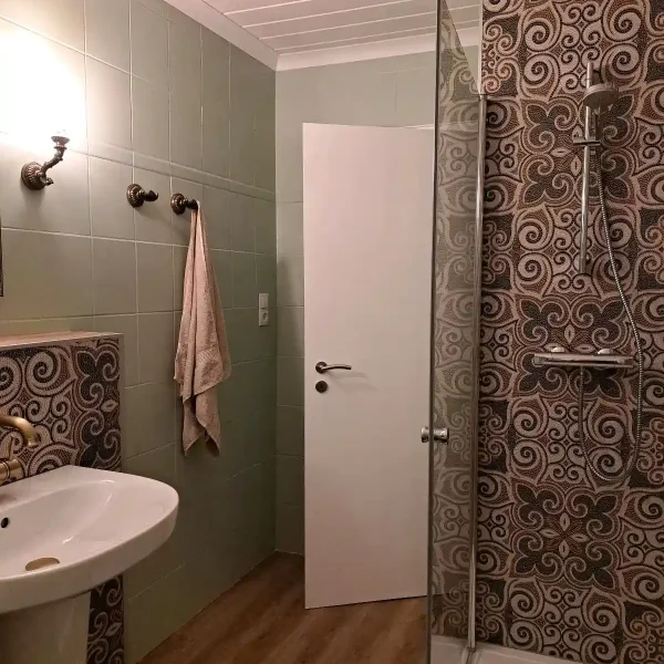 Ferienwohnung Rastede: Modern saniertes Badezimmer im Erdgeschoss mit ebenerdiger Dusche und Design-Fliesen.