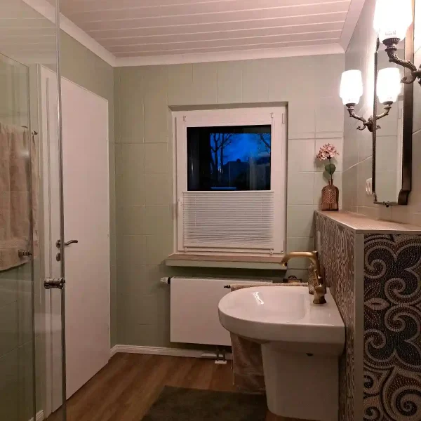 Unterkunft Ammerland: Elegantes Waschbecken mit Gold-Armaturen und Vintage-Beleuchtung in Hahn-Lehmden.