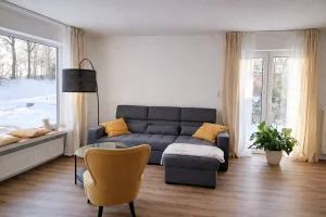 Ferienhaus Niedersachsen: Modernes Wohnzimmer mit Sofa und gelbem Sessel für Urlaub nahe der Nordsee.