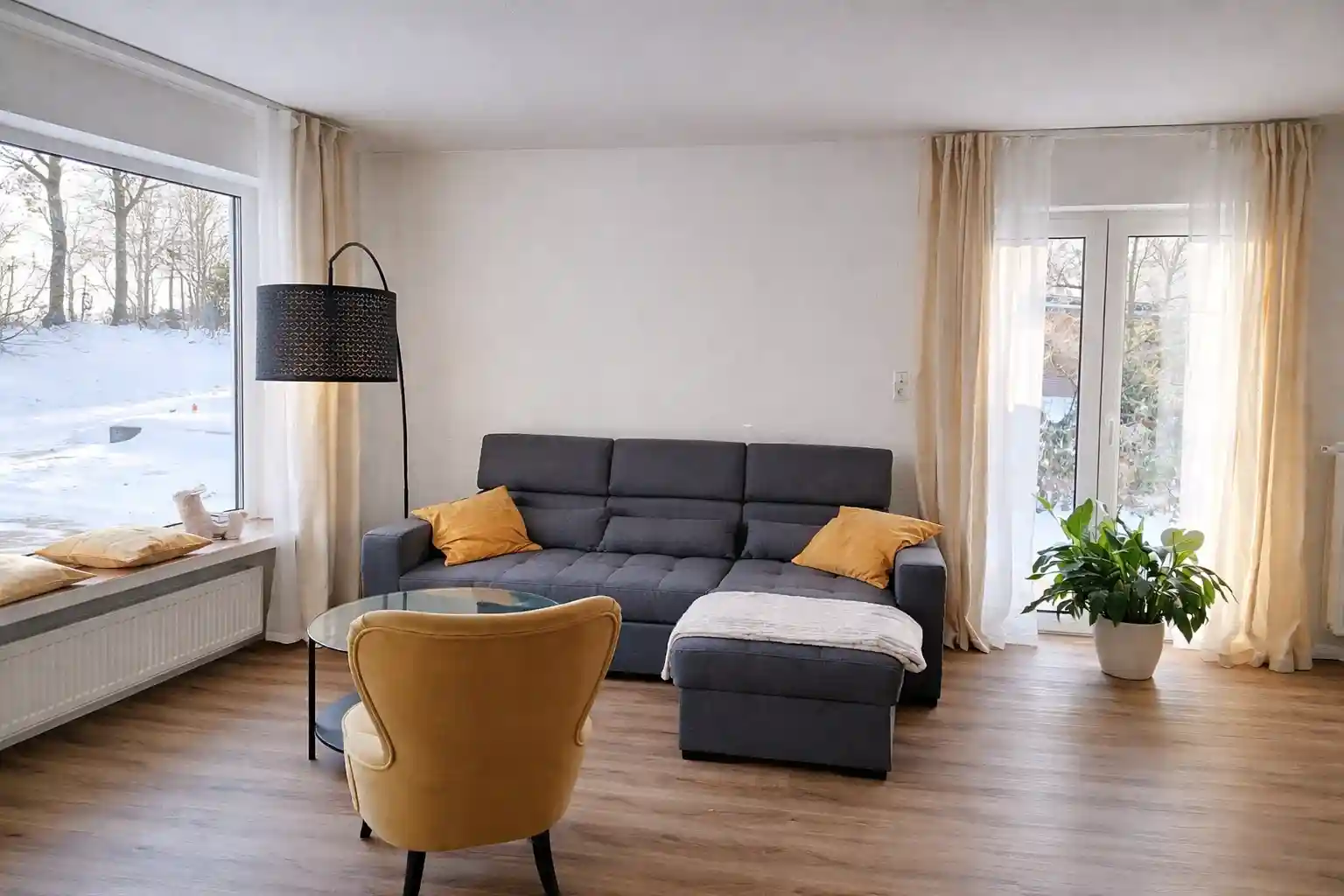 Ferienhaus Niedersachsen: Modernes Wohnzimmer mit Sofa und gelbem Sessel f&uuml;r Urlaub nahe der Nordsee.