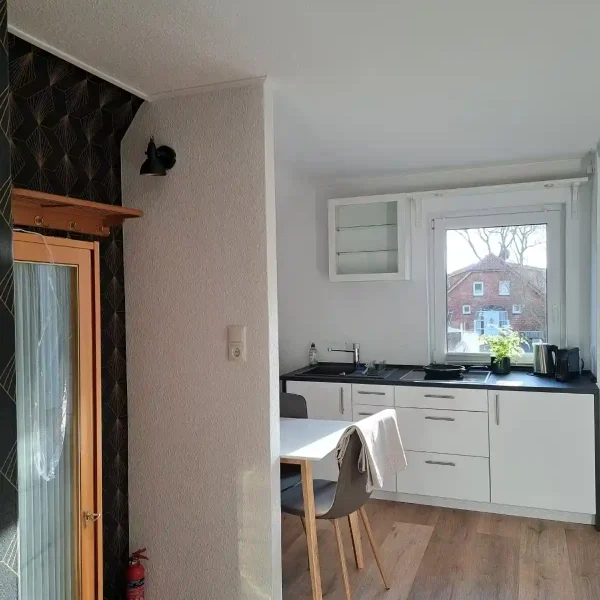 Hahn im Grün: Stilvoller Flurbereich mit Übergang zur modernen weißen Küche in der Unterkunft Rastede.