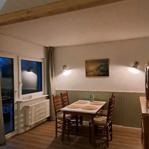 Ferienwohnung Hahn-Lehmden: Rustikaler Essplatz mit Holzstühlen und grüner Wandvertäfelung im Ammerland.