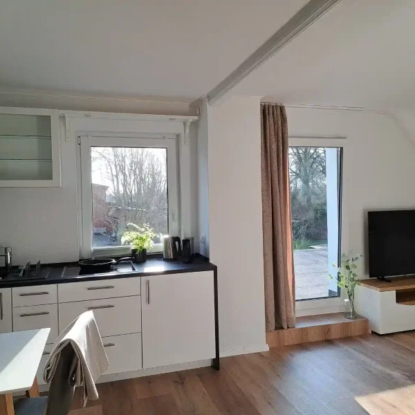 Ferienwohnung Hahn-Lehmden: Offener Wohn- und Kochbereich mit TV-Ecke und viel Tageslicht im Ammerland.