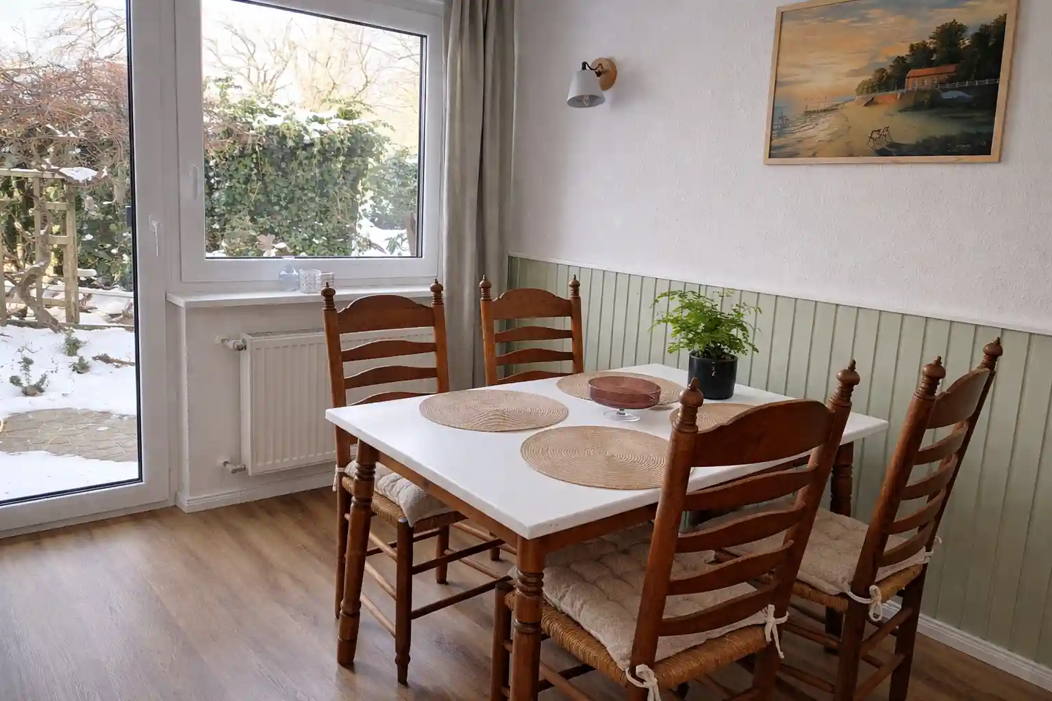 Radurlaub Ammerland: Ebenerdige Ferienwohnung mit hellem Essplatz und rustikalen Holzst&uuml;hlen am Fenster.