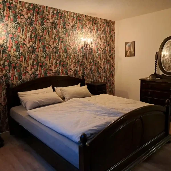 Unterkunft Hahn-Lehmden: Stilvolles Schlafzimmer-Interieur mit antikem Spiegelschrank und Kunst-Details.