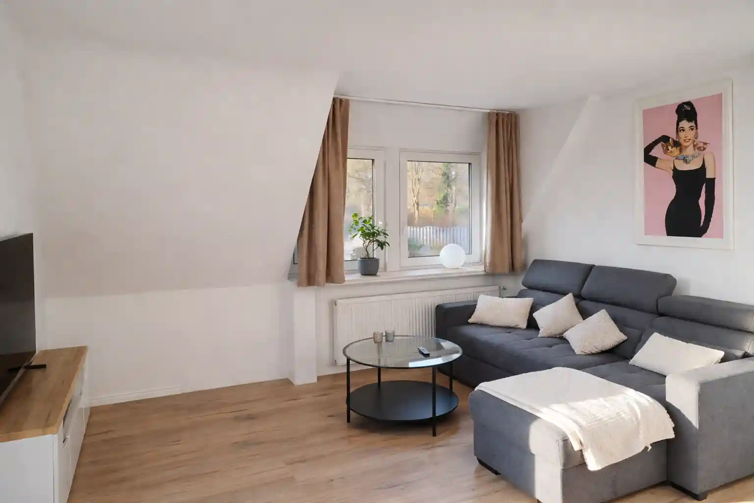 Unterkunft Rastede: Modernes Wohnzimmer mit grauem Sofa in der Ferienwohnung Hahn.