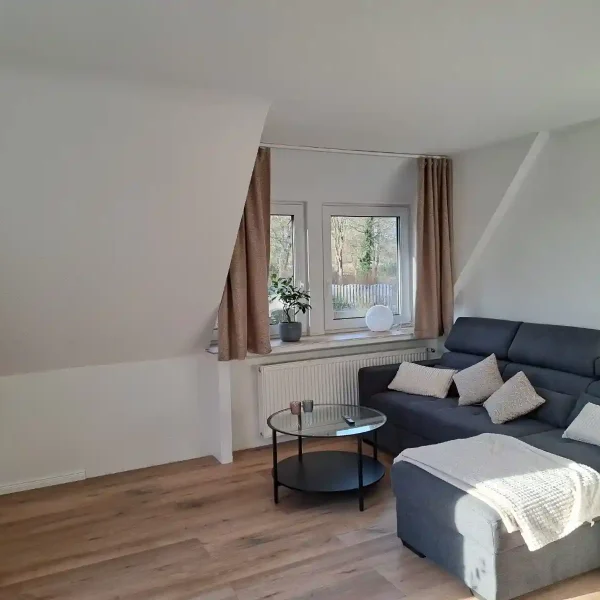 Ferienwohnung Rastede: Helles Wohnzimmer im Obergeschoss mit grauem Sofa und Audrey Hepburn Pop-Art.